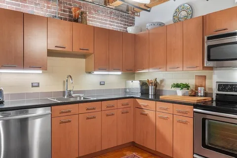 a kitchen with stainless steel appliances granite countertop a sink a stove and cabinets