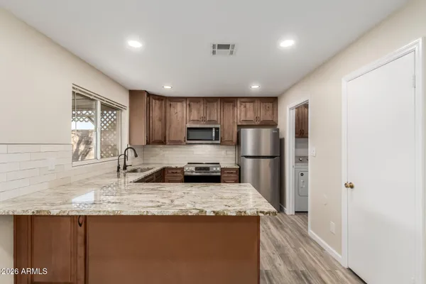 a kitchen with stainless steel appliances granite countertop a sink stove refrigerator and cabinets
