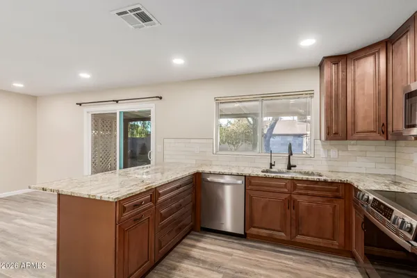 a kitchen with stainless steel appliances granite countertop wooden cabinets a sink and a stove