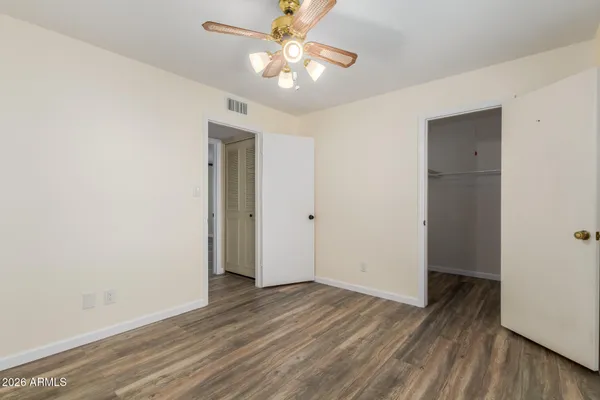 an empty room with wooden floor and a ceiling fan