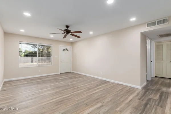 a view of empty room with wooden floor and fan