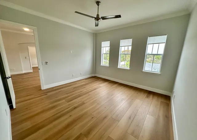 a view of empty room with wooden floor and fan