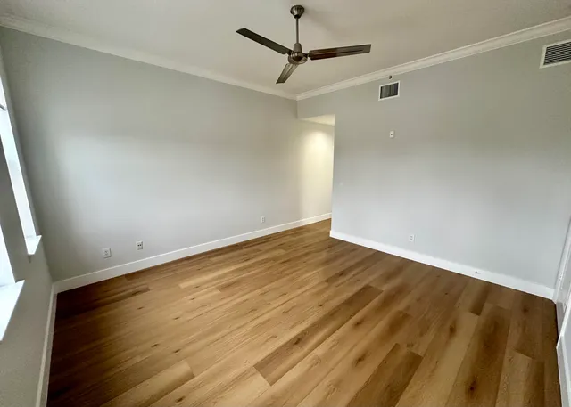 an empty room with wooden floor and windows