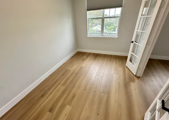 an empty room with wooden floor and windows