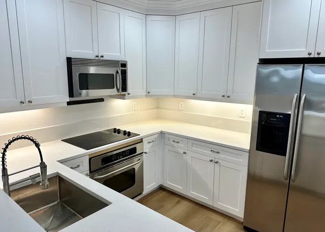 a kitchen with granite countertop white cabinets and stainless steel appliances