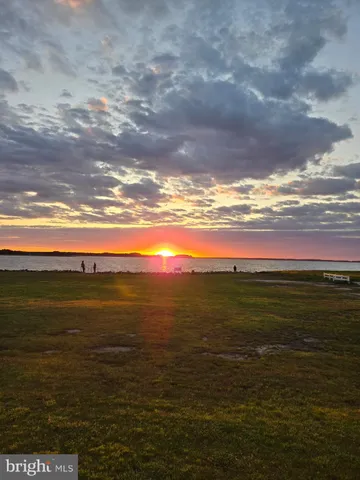 a view of a kitchen with kitchen island a large window cabinets a sink and stainless steel appliances