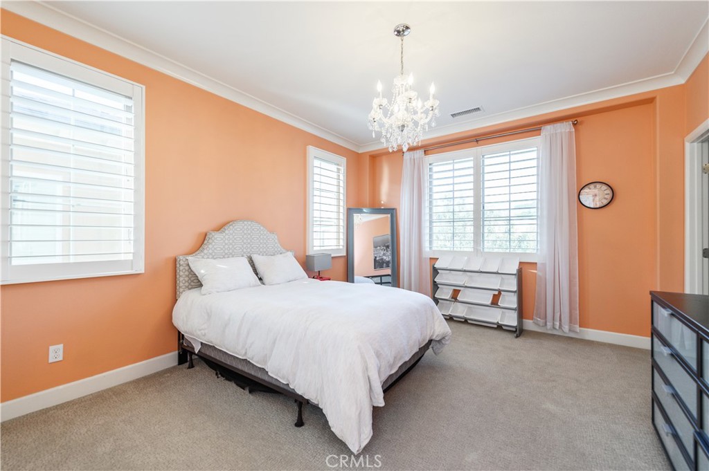 126 Long Fence Irvine, CA 92602 - Photo 44 of 61 a spacious bedroom with a bed and a chandelier