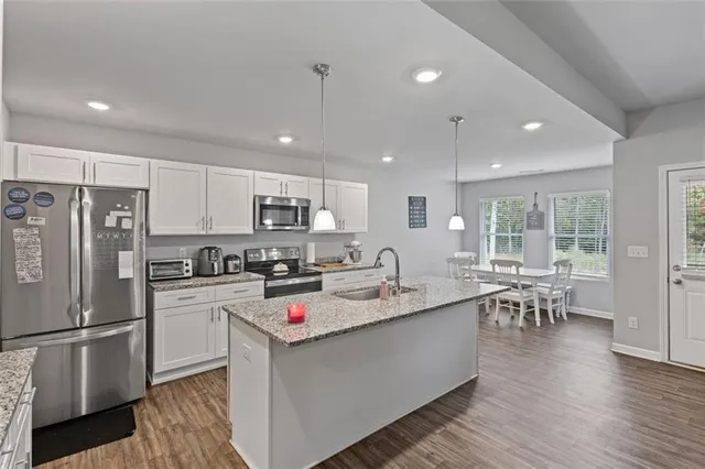 a large kitchen with stainless steel appliances granite countertop a lot of counter space and wooden floors