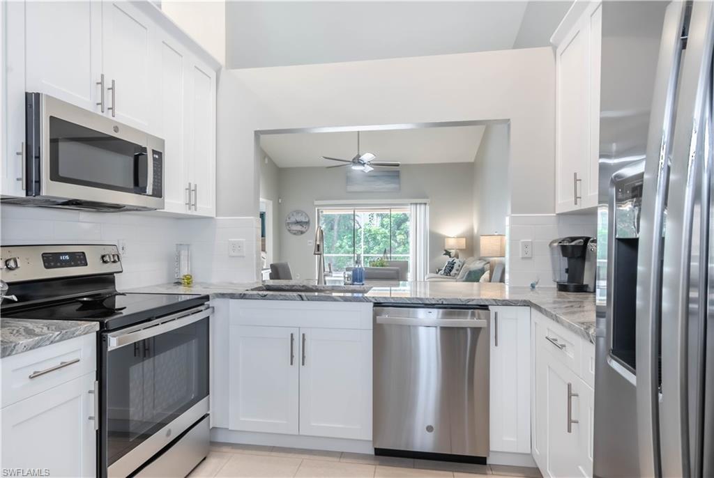 480 St Andrews Boulevard, Unit 14 Naples, FL 34113 - Photo 7 of 24 a kitchen with stainless steel appliances granite countertop a sink and a microwave