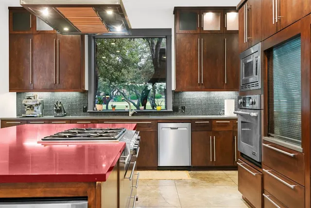 a kitchen with stainless steel appliances granite countertop a stove a sink and a microwave