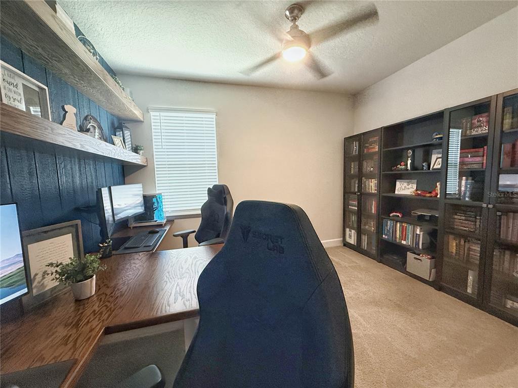 3181 Hill Point Street Minneola, FL 34715 - Photo 40 of 52 a living room with furniture a lamp and a bookshelf