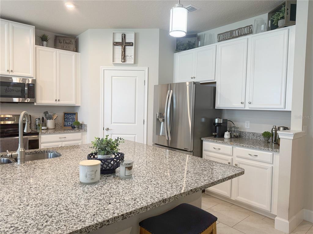 3181 Hill Point Street Minneola, FL 34715 - Photo 4 of 52 a kitchen with stainless steel appliances granite countertop a refrigerator a stove and white cabinets