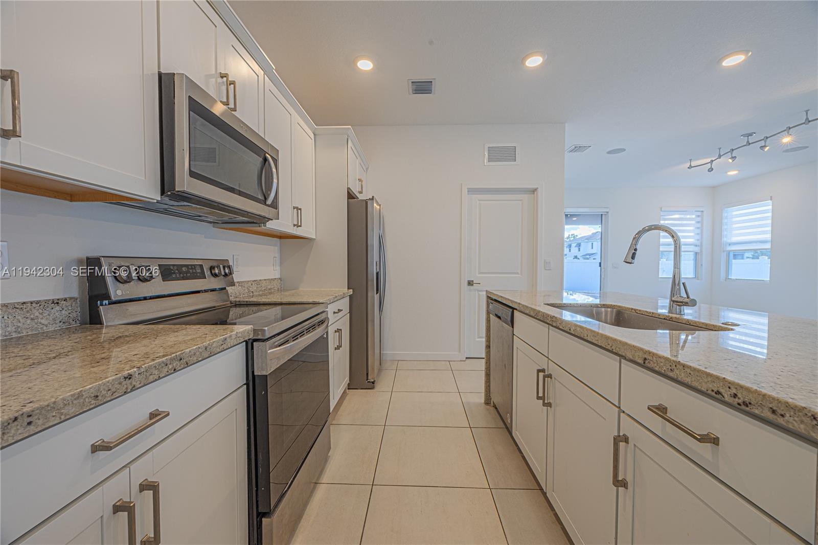 7214 Rockwood Road Jupiter, FL 33458 - Photo 18 of 28 a kitchen with stainless steel appliances granite countertop a sink and a stove