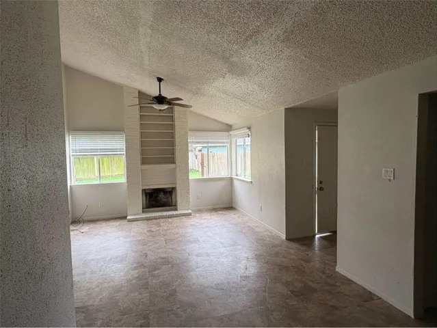 an empty room with windows and a fireplace