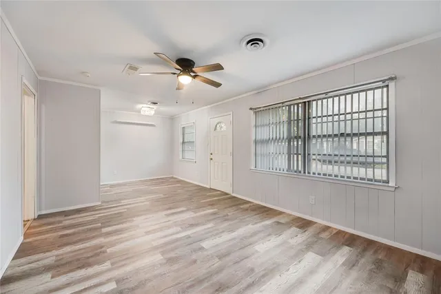 a view of empty room with wooden floor and fan