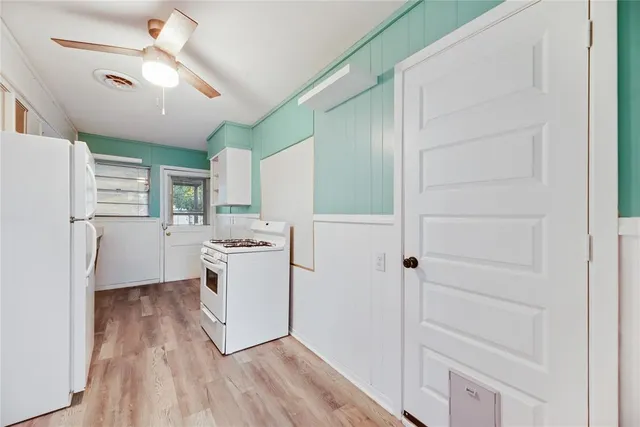 a kitchen with a refrigerator a stove top oven and a ceiling fan