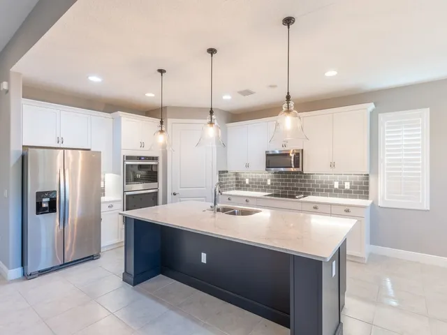 a kitchen with kitchen island a refrigerator a sink a stove and chairs with wooden floor