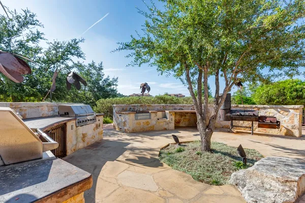 a view of a patio with table and chairs a fire pit and large trees