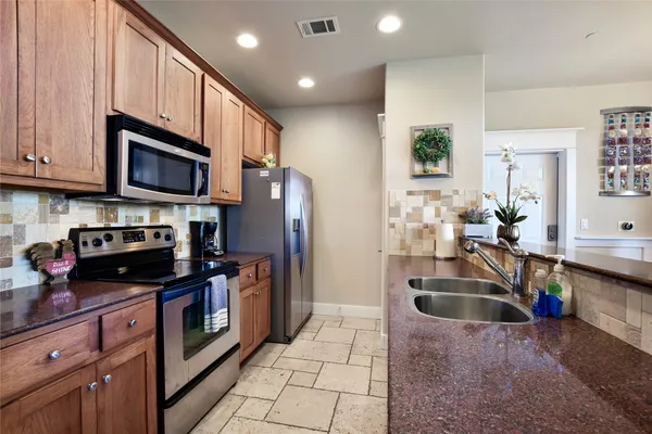 a kitchen with kitchen island granite countertop a sink a counter top space appliances and cabinets