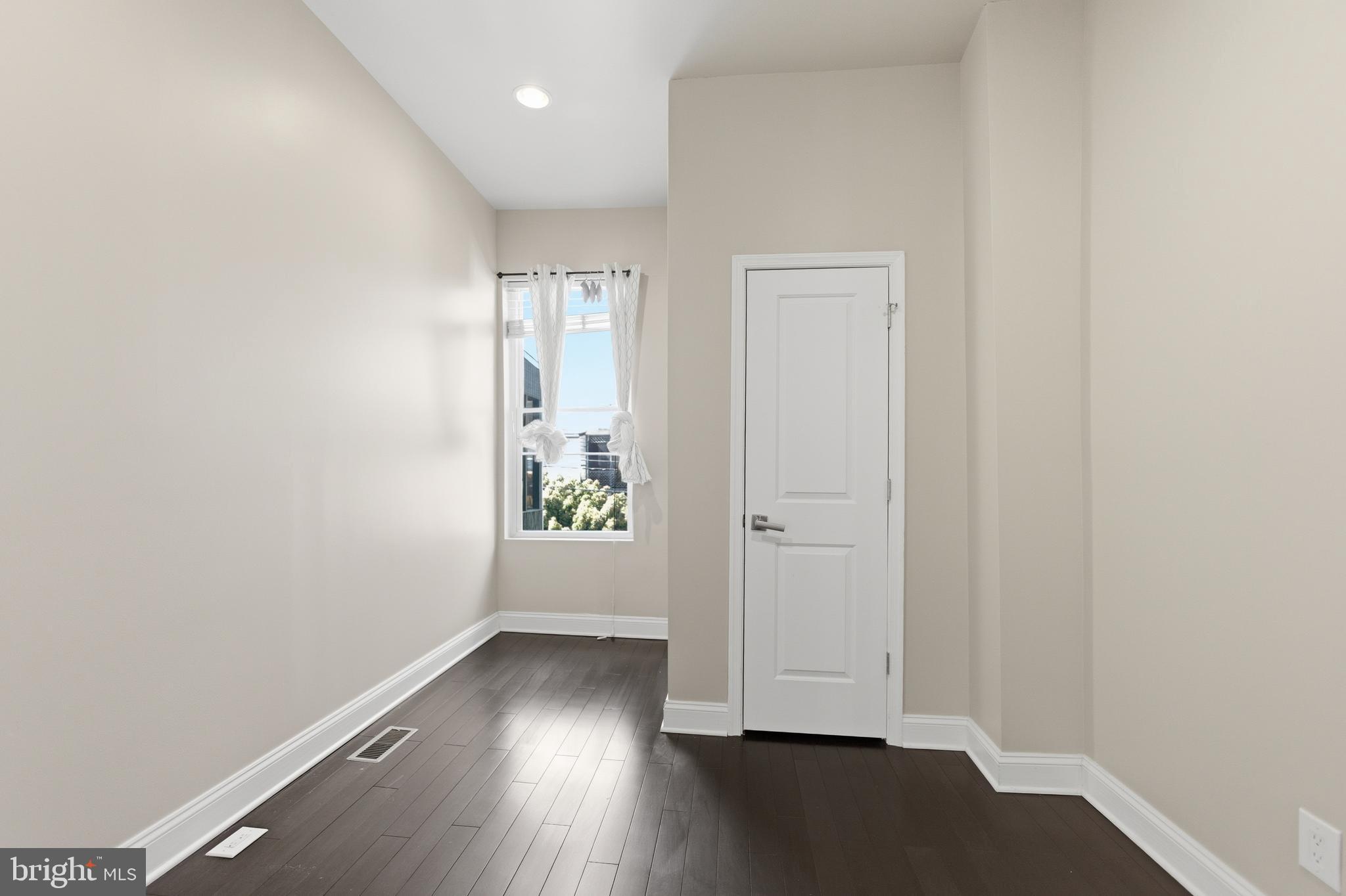 10 Girard Street Northeast Washington, DC 20002 - Photo 26 of 31 an empty room with wooden floor and windows