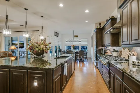 a kitchen with stainless steel appliances granite countertop a sink a stove and a wooden floors