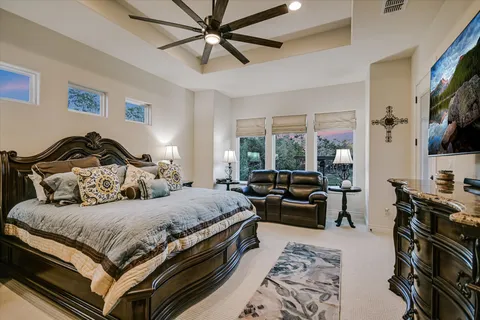 a bedroom with a bed a couch and a flat tv screen on dresser