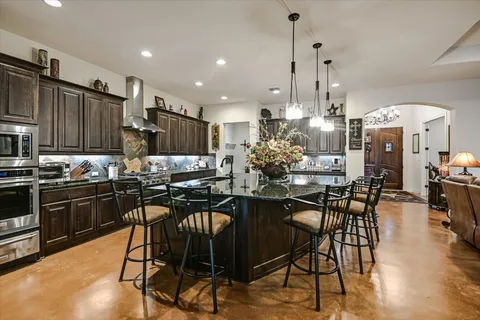 a kitchen with stainless steel appliances kitchen island granite countertop a table chairs stove and cabinets
