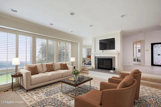 a living room with furniture fireplace and a large window
