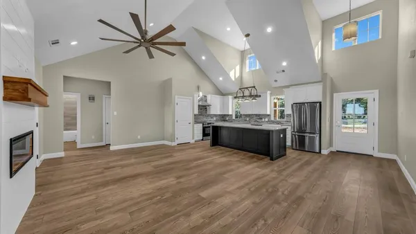 a view of an empty room with kitchen and a fireplace