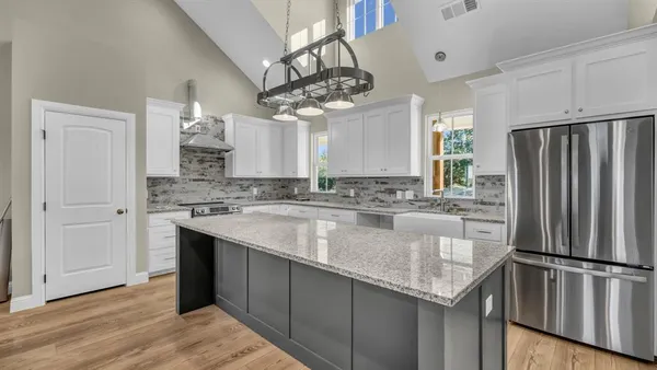 a kitchen with a center island wooden floor and stainless steel appliances