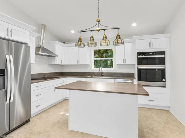 a kitchen with kitchen island a counter space a sink appliances and cabinets