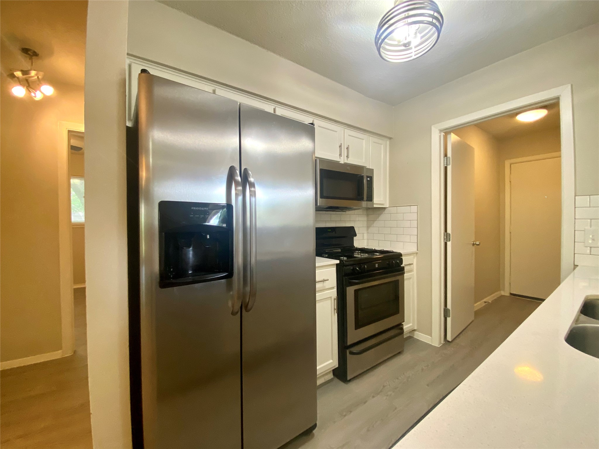 6400 Brookside Drive Austin, TX 78723 - Photo 14 of 26 Kitchen with appliances with stainless steel finishes, light countertops, white cabinetry, and tasteful backsplash