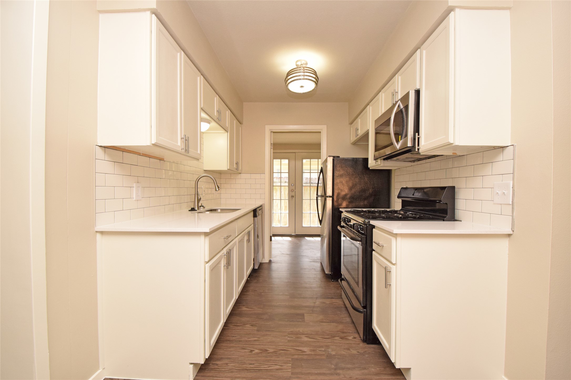 6400 Brookside Drive Austin, TX 78723 - Photo 21 of 26 Kitchen featuring stainless steel appliances, wood finished floors, light countertops, white cabinetry, and backsplash