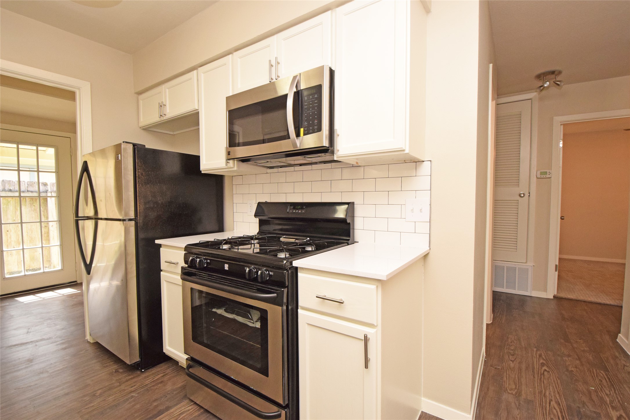 6400 Brookside Drive Austin, TX 78723 - Photo 22 of 26 Kitchen with appliances with stainless steel finishes, tasteful backsplash, dark wood-type flooring, white cabinetry, and light countertops