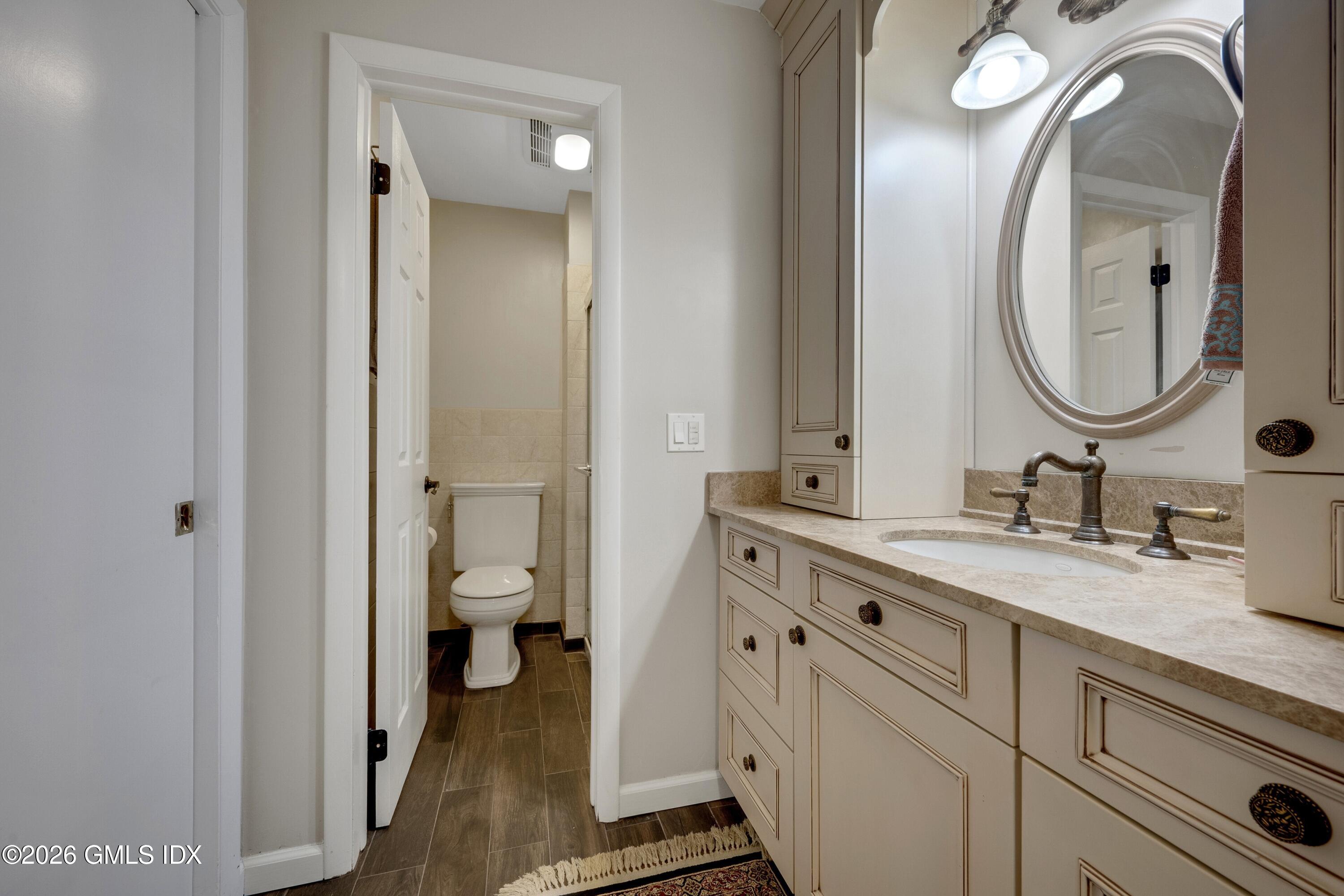 58 Stirrup Lane, Unit 58 Riverside, CT 06878 - Photo 9 of 23 a en suite bathroom with a granite countertop toilet sink and a mirror