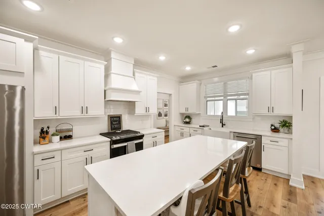 a kitchen with a sink a stove a refrigerator and white cabinets