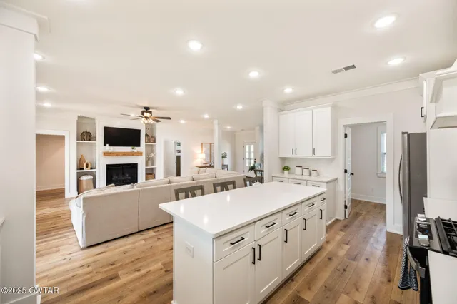 a large white kitchen with stainless steel appliances a stove a refrigerator a oven and a refrigerator with wooden floor