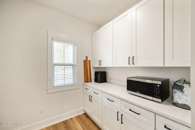 a kitchen with white cabinets and window