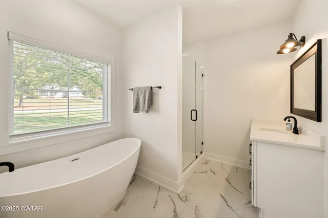 a bathroom with a tub a sink a mirror and a window