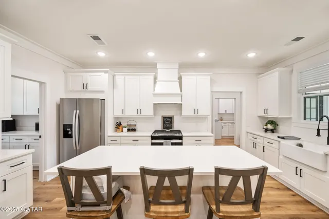 a kitchen with a dining table chairs refrigerator and cabinets