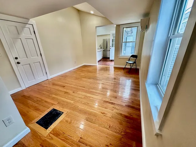a view of an empty room with wooden floor and a window