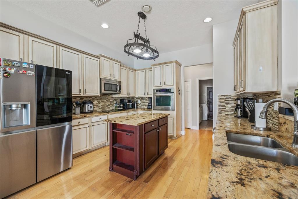 22623 Cliffside Way Land O' Lakes, FL 34639 - Photo 15 of 49 a large kitchen with stainless steel appliances granite countertop a stove refrigerator and a sink with cabinets