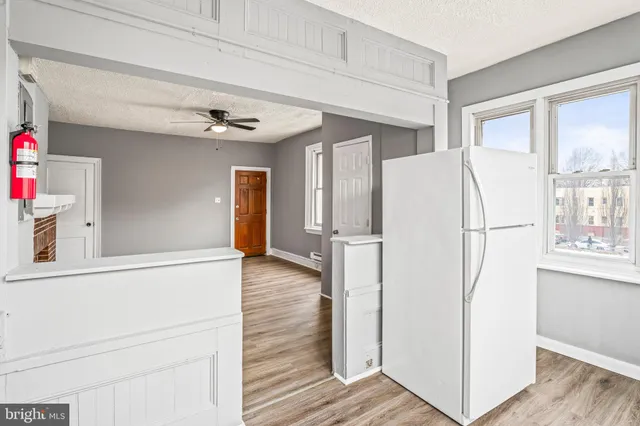 a view of a kitchen with refrigerator and wooden floor