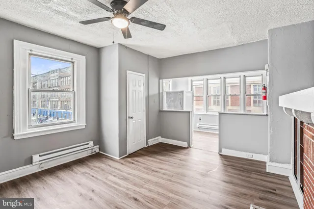 a view of an empty room with a window and wooden floor