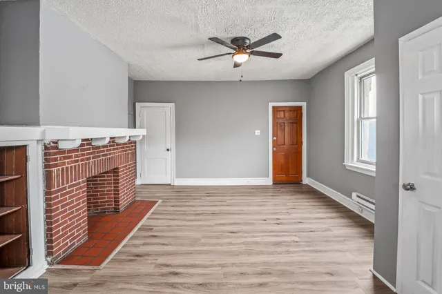 a view of an empty room with window and wooden floor