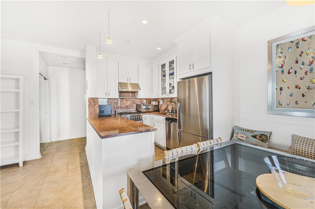286 Corbin Place, Unit 5E Brooklyn, NY 11235 - Photo 8 of 35 a kitchen with stainless steel appliances granite countertop a refrigerator a sink a stove and white cabinets with wooden floor