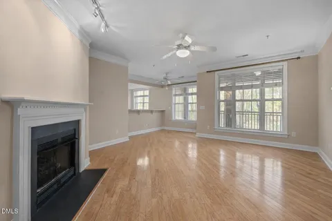 an empty room with wooden floor fireplace and windows