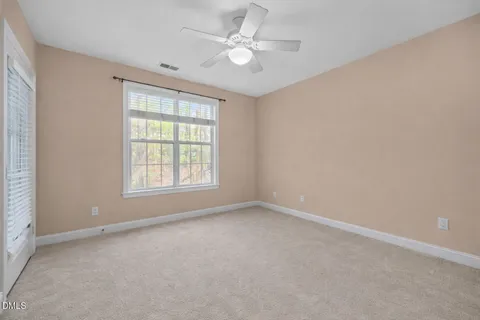 an empty room with windows and ceiling fan