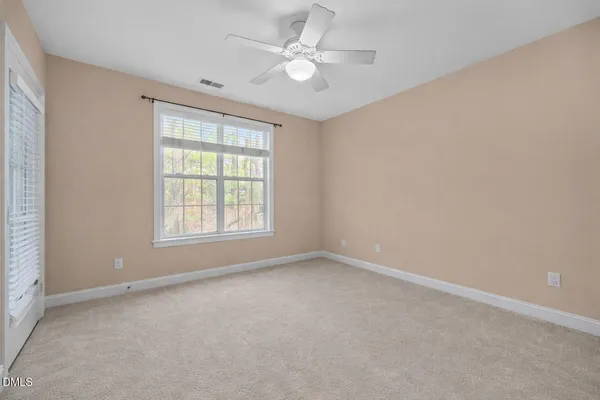 an empty room with windows and ceiling fan