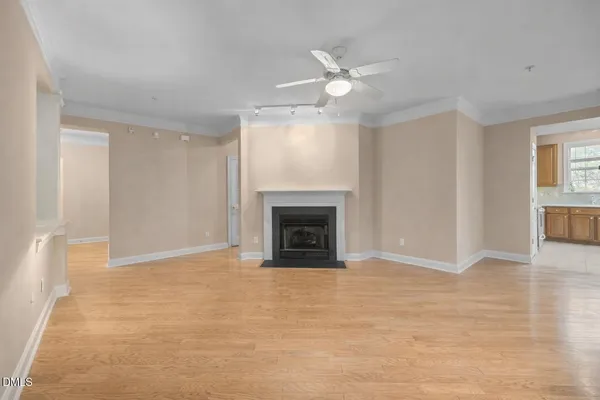 a view of an empty room with chandelier fan and fire place
